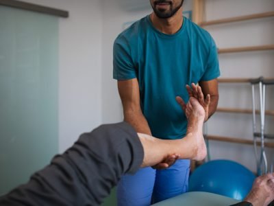 A close-up of physiotherapist exercising with senior patient's leg in a physic room.