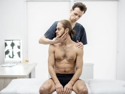 Physical therapist does manual therapy to a young athletic guy at medical office. Concept of manual therapy and osteopathy