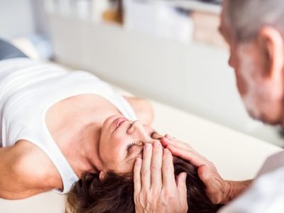 Unrecognizable senior physiotherapist working with an old female patient.